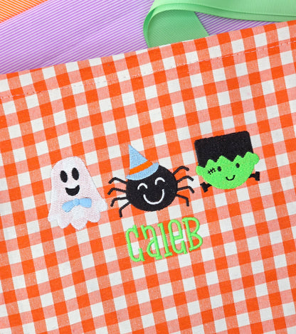 Halloween-themed design with ghost, spider, and green creature on gingham halloween candy basket. Candy pale