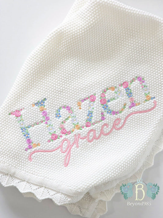 "Personalized ivory knit baby blanket with floral embroidered name and pink script embroidery.
.