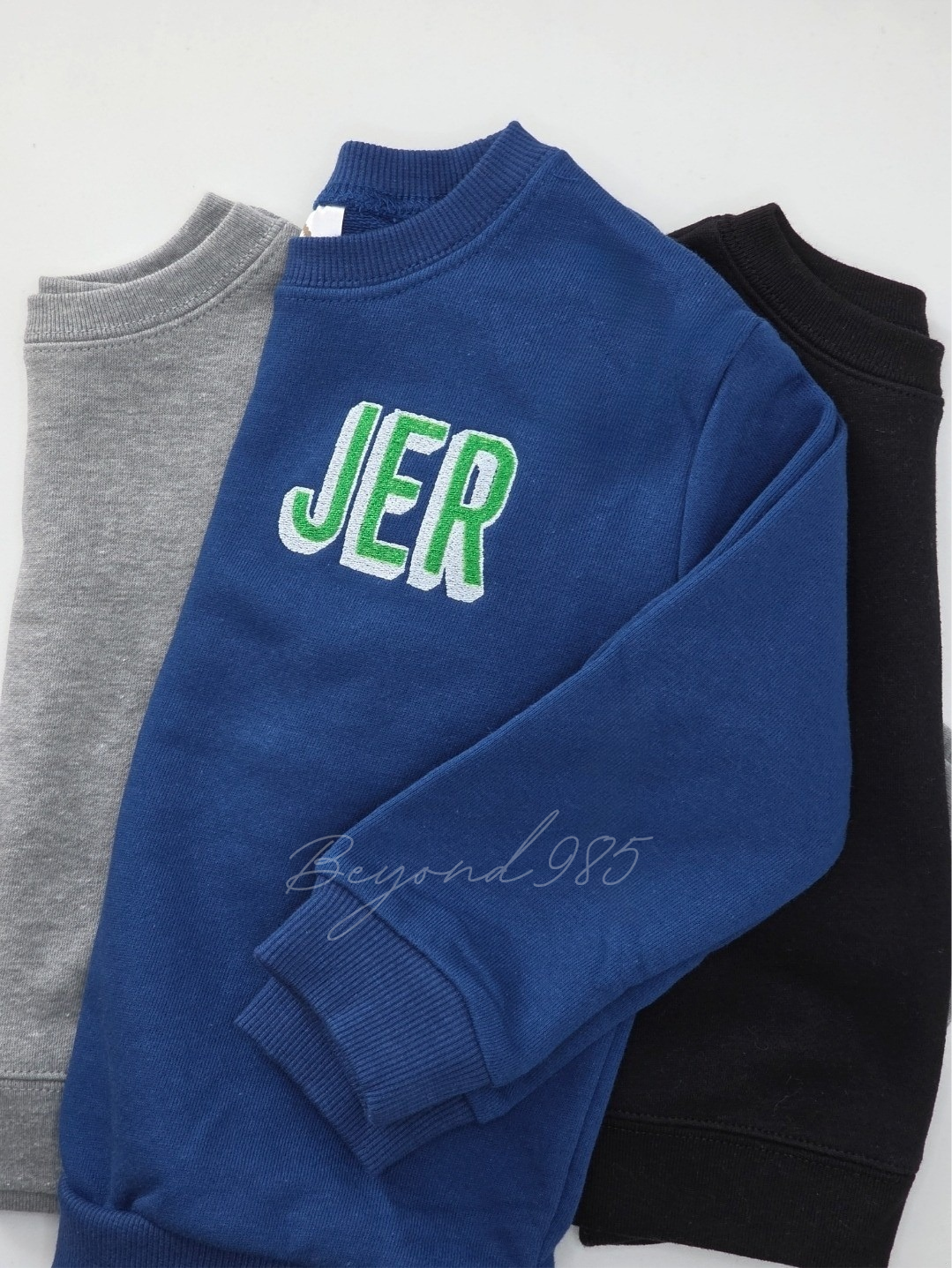 Blue sweatshirt with 'JER' text, gray and black sweaters in the background