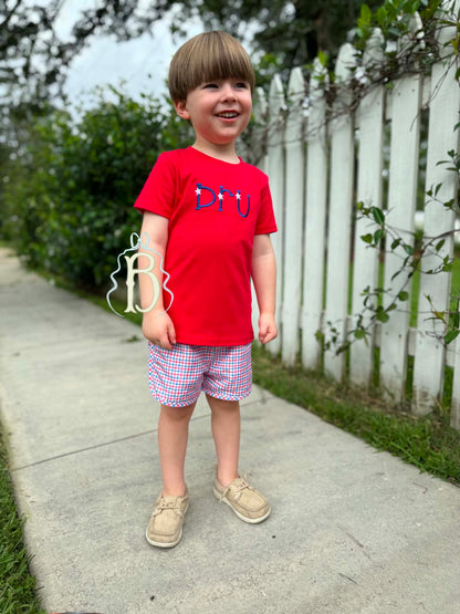 Toddler boy wearing personalized red patriotic embroidered shirt with red white and blue plaid shorts
