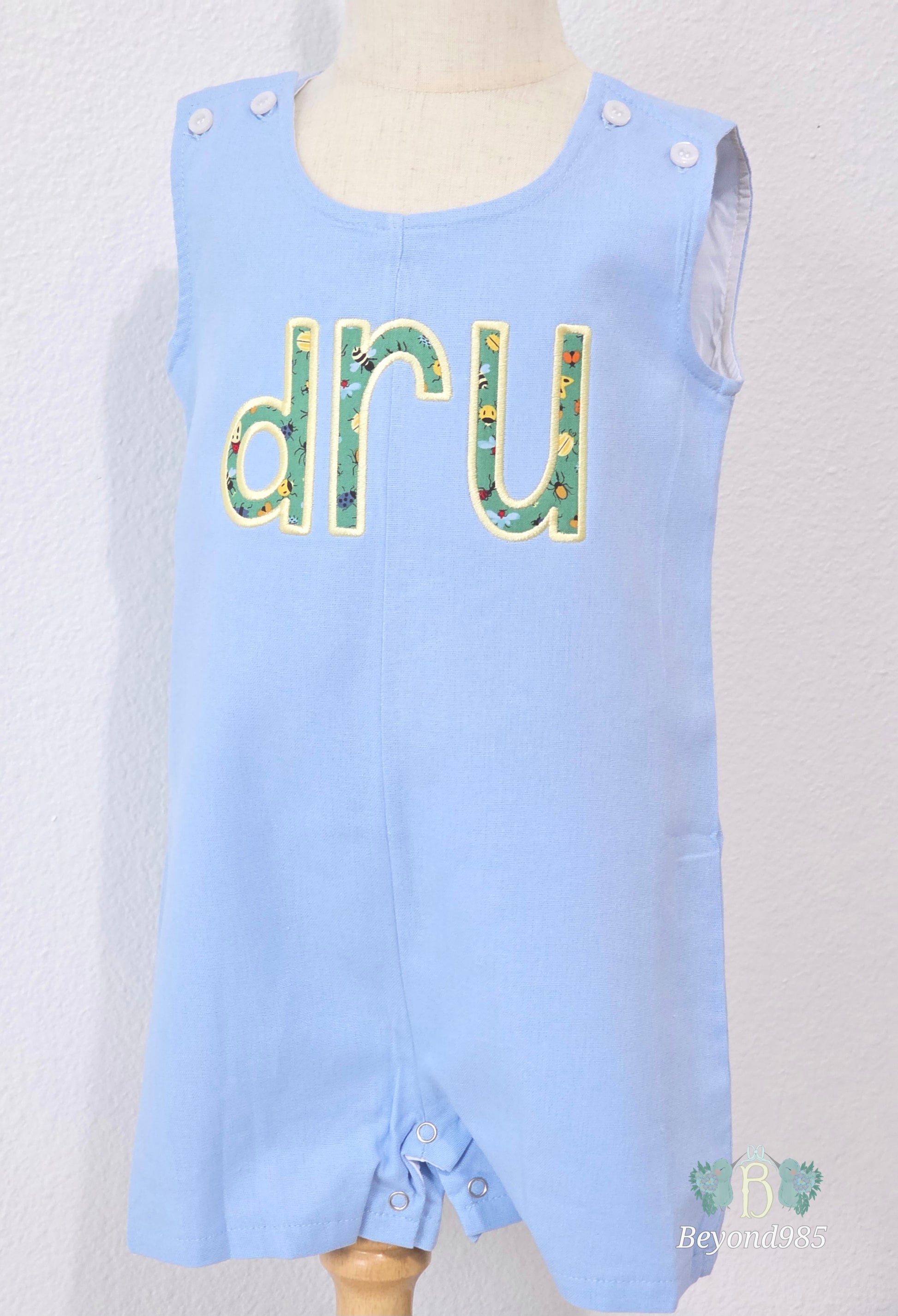 Personalized blue boys shortall with custom applique name Dru embroidered across the chest
